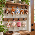 Nine crochet animal key pouches hanging from hooks by a front door, each with a house key.