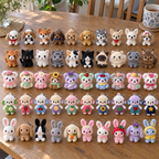 Fifty crochet animal keychains on a wooden dining table in five rows: ten dogs, ten cats, ten plush bears, ten curly sheep and ten bunnies.