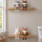 Cat, Bear, Bunny and Fox crochet reading roll holders on two wooden bathroom wall shelves.