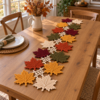 A multicoloured maple leaf crochet runner with ivory open connections on a honey-oak dining table.