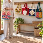 A lady applique tote carried on an arm, with sunflower, Christmas gnome, Log Cabin and granny mesh bags hanging beside a wooden entry bench.