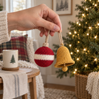 An adult hand holding one small red crochet bauble and one gold crochet bell by their natural-tan yarn loops.