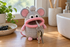 Light-grey Mouse crochet key pouch with pink-lined round ears, pink limbs and a long pink tail, with house keys hanging from its pink-lipped mouth.