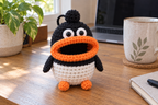 Penguin crochet key pouch with a white body, black head and flippers, orange feet and an orange rolled lip around an open, empty mouth.