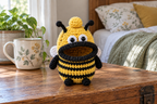 Yellow Bee crochet key pouch with black body stripes, black antennae and limbs, white wings and a black rolled lip around an open, empty mouth.