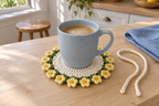 Buttercup: a blue coffee mug on a flat warm-white crochet coaster with small yellow buttercups and green leaves.