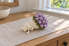 Lilac: a tied warm-white crochet bouquet with lilac star flowers and green leaves on a linen runner.