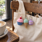 Cupcake, ice cream cone and macaron crochet charms hanging from a canvas tote on a cafe chair.
