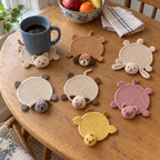 Mug Buddies crochet coasters on a table: Cat, Dog, Rabbit, Sheep, Cow, Pig, Chick.