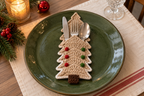 Gingerbread crochet cutlery holder with tan panels, white edging and red and green candies, holding a knife, fork and spoon on a Christmas table.