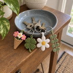 Bouquet, clover, daisy and eucalyptus crochet keychains on keys in a ceramic dish by the front door.