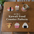 Six food-shaped crochet coasters on a wooden table with a mug on the donut, surrounding the title 21-in-1 Kawaii Food Coaster Pattern.