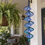 A blue and teal lace crochet spinner with bluebell flowers hanging on a porch beside a fern basket