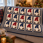 Navy-framed Nordic gnome blanket with alternating navy and red hats draped over a sofa back beside a mug of cocoa.