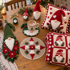 Eight crochet pieces on a wooden table: a Christmas Tree keychain, red gnome bauble, Green Holly coaster with a mug, Classic shelf gnome, Poinsettia door hanger, Heart Gnome pillow, Christmas doily and folded red gnome blanket.