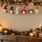 Six round Christmas gnome baubles with red, green, white, striped, Nordic and gold hats hanging from a birch branch.