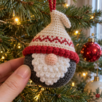 A close view of a Nordic gnome bauble shows its red bobble brim, peach nose and white textured beard.