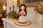 Angel crochet pattern: cream robe and wings, brown curls, gold halo and a gold star, on a scalloped doily by candlesticks.