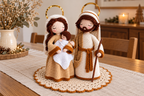 Holy Family crochet pattern: Mary holding the swaddled Baby beside Joseph with his straight staff, gold halos, on a scalloped doily on a dining table.