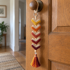A Sunset Chevron crochet ornament hanging from a wooden door handle.