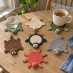 Frog, duck, turtle, otter, penguin, seal and octopus crochet coasters on a wooden table, with a water glass on the frog and a tea mug on the turtle.