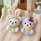 Cream Bunny Hood Bear with a mint hood and sky blue Cherry Bear with a yellow collar clipped to a canvas tote strap.