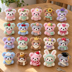Twenty distinct crochet bear keychains in four rows on a wooden table, with flowers, fruit, bows, hats and matching neck accessories.