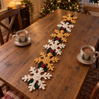 Snowflake Garland crochet table runner with alternating ivory and gold snowflakes, holly leaves and red berries on a kitchen table in the evening.
