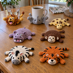 Seven Safari Friends crochet coasters. Cups on selected discs tip the heads and legs up; empty coasters rest as low domes with their appendages splayed on the table.