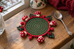 Holly Christmas crochet mushroom coaster: green base, red edge, red caps, white spots, four holly leaves with red berries, with no cup, the mushrooms lying out round the rim.