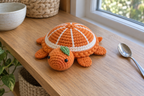 Orange Slice pop-up crochet turtle coaster, orange segments divided by white spokes, with a green leaf, shown with no cup, a rounded domed shell with its head and feet resting.