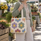 A woman carries a Flower Garden hexagon crochet tote filled with vegetables at a farmers market.