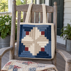A Log Cabin crochet tote hangs on a wooden porch rocking chair above a folded quilt.
