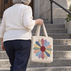 A Dresden Plate crochet tote with a hardback book is carried on stone library steps.
