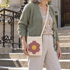 Flower Garden crochet phone bag worn crossbody with a cardigan on stone steps.