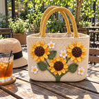 Cream crochet tote with mustard handles, yellow sunflowers and white daisies on a cafe bench beside a straw hat and iced drink.