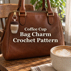 Cream crochet coffee-cup bag charm with a kraft tan sleeve and brown tiered lid hanging from a silver ring on a brown leather handbag beside a coffee mug.