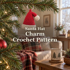 A small red crochet Santa hat with an off-white brim and pom hangs from a silver ring on a Christmas tree branch in a cosy living room, with the title Santa Hat / Charm / Crochet Pattern.