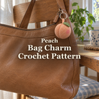 A peach crochet bag charm with a pink cheek and green leaf hangs from a tan leather handbag on a wooden chair beside a sunny window, with the title Peach Bag Charm Crochet Pattern.