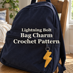 Amber crochet lightning bolt hanging from the front pocket zipper of a navy backpack on a wooden chair beside a bedroom window.