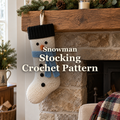 Ivory snowman crochet stocking with a black cuff, orange nose and sky-blue scarf hanging from a wooden Christmas mantel, with the title Snowman Stocking Crochet Pattern.