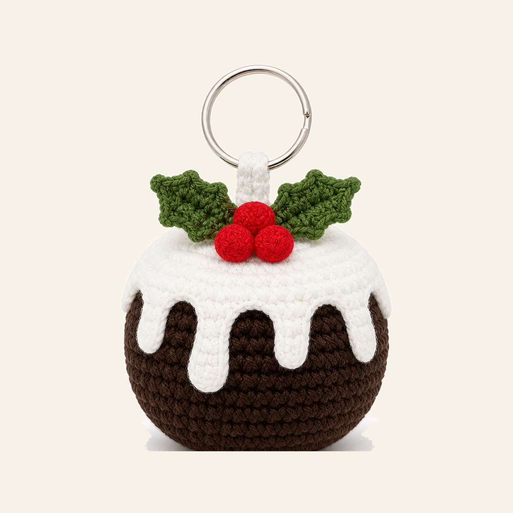 Crochet Christmas pudding ornament with a white icing cap and holly