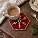Ruby-red Ruby Lace hexagonal crochet coaster with gold edging and a ring-centred ivory snowflake beneath a cream teacup on a wooden table.