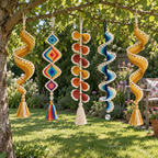 Five crochet wind spinners with gold spirals, rainbow diamonds, warm-coloured petals and blue scalloped lace hang from one garden tree above a lawn.