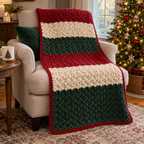 Red, cream and forest green striped crochet throw with a red border draped over an armchair beside a lit Christmas tree.