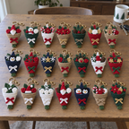 Twenty-one Christmas crochet bouquet designs arranged in three rows on a wooden dining table.