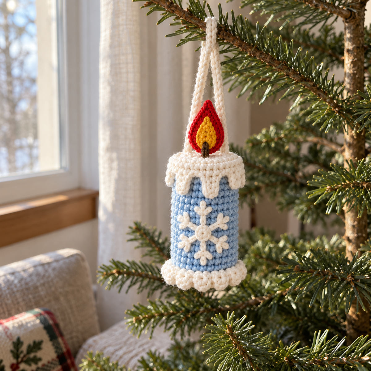 A pale blue crochet candle ornament with a white snowflake and scalloped white base hangs from a Christmas tree branch beside a window.