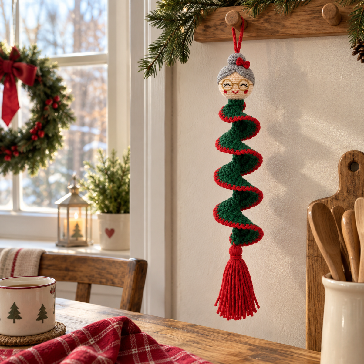 Mrs Claus with grey hair, a red bow and round gold spectacles hangs from a wooden peg above a kitchen table, with a green and red ruffle and red tassel.