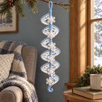 A white crochet lace spiral with pale blue edging and small white snowflakes hanging from a pine branch beside a window and armchair.