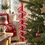 A red-and-white crochet lace spiral with peppermint pinwheel motifs hanging by its yarn loop from a Christmas tree branch.